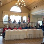 Students sitting at table while a person speaks into mic at the Mechanicville CSD 2nd Annual Educator P2 Summit