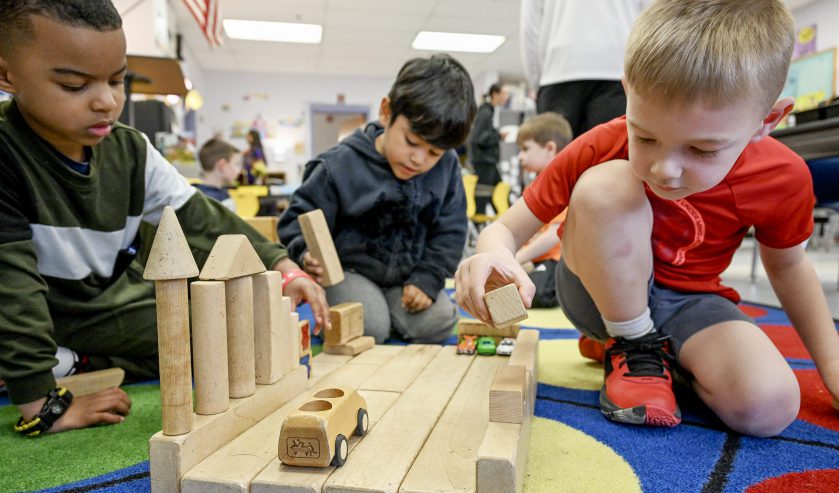 3 elementary students playing with blocks on a carpet