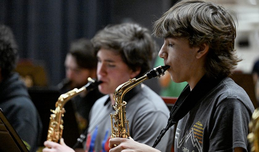 two students playing saxophone