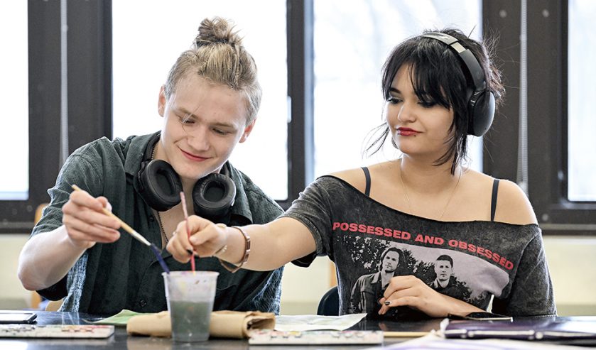 two students painting in art class