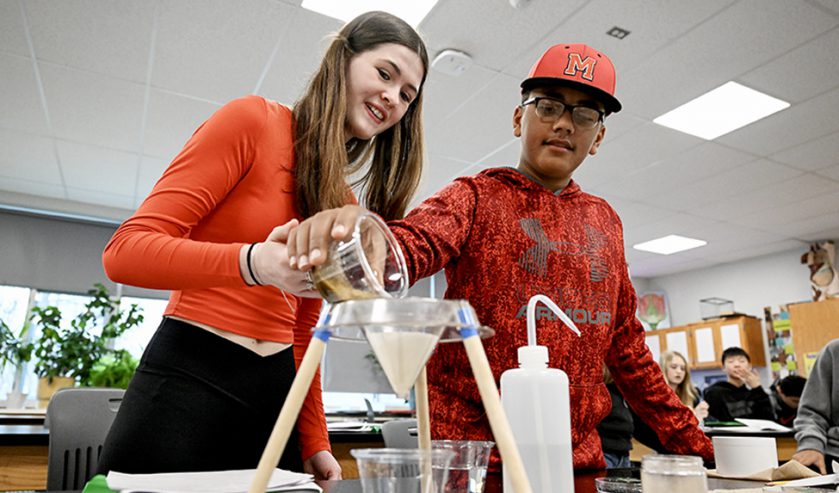 Two students in science lab performing a lab experiment.